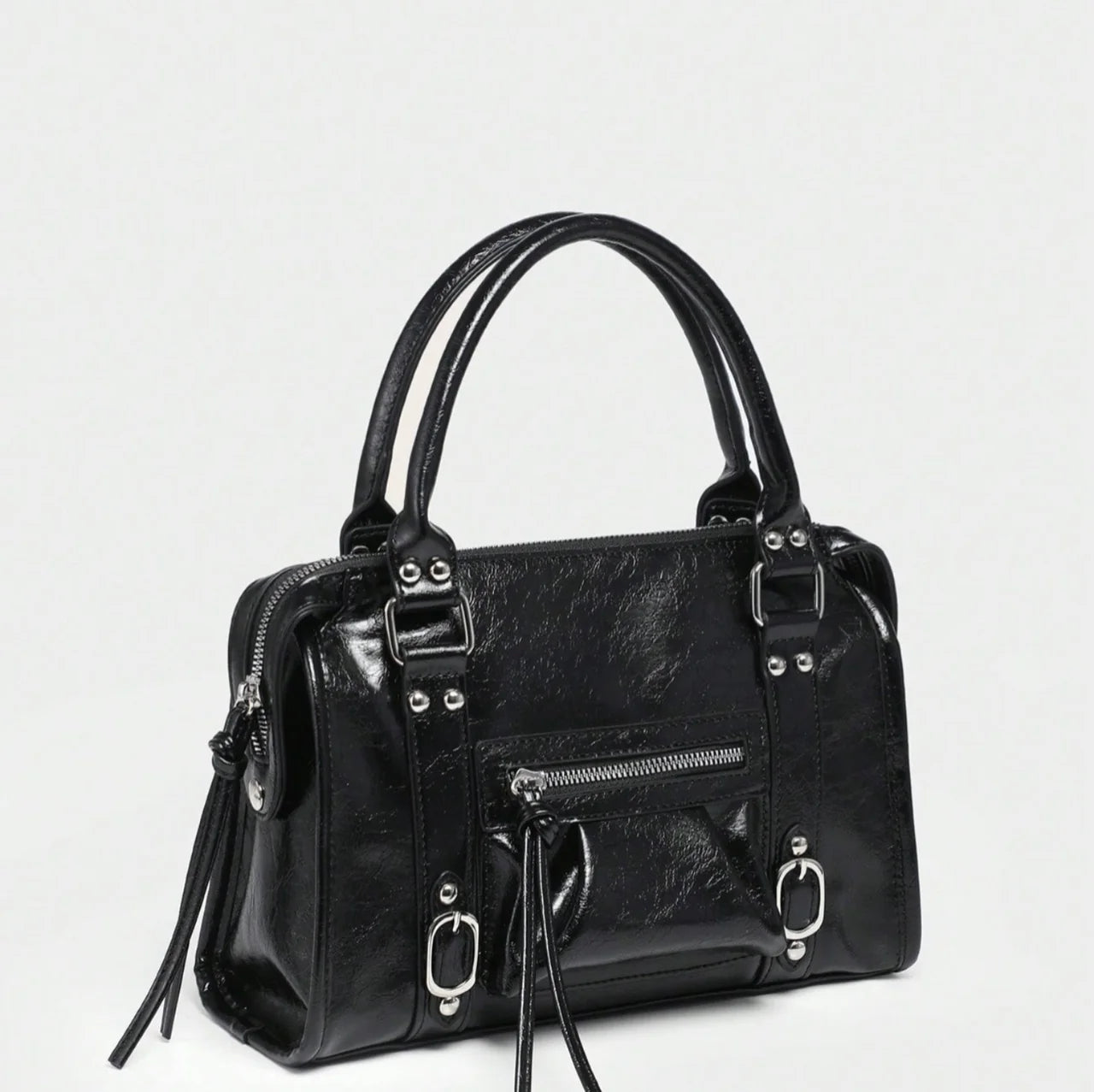 Sac à main CARLA en cuir noir effet brillant, avec détails métalliques, finitions soignées, anses solides, bandoulière réglable et grand compartiment zippé, parfait pour le travail et les sorties; vue de coté.