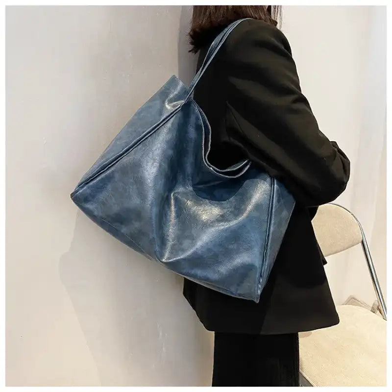 Sac à main LORIA en cuir synthétique bleu, moderne et chic, avec bandoulière ajustable, intérieur spacieux et compartiments organisés, parfait pour le quotidien et les sorties, porté épaule.