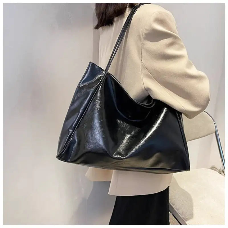 Sac à main LORIA en cuir synthétique noir, moderne et chic, avec bandoulière ajustable, intérieur spacieux et compartiments organisés, parfait pour le quotidien et les sorties, porté épaule.