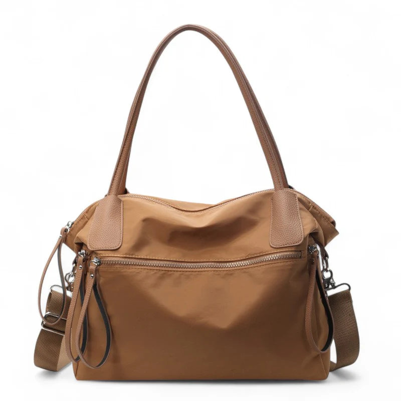 Sac à main NARA marron en toile résistante, léger et pratique, avec bandoulière ajustable, offrant grande liberté de mouvement pour vos essentiels du quotidien.