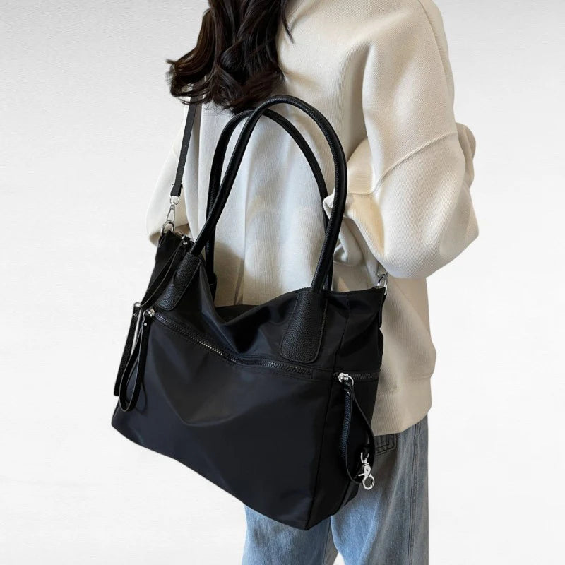 Sac à main NARA NOIR en toile résistante, léger et pratique, avec bandoulière ajustable, offrant grande liberté de mouvement pour vos essentiels du quotidien.