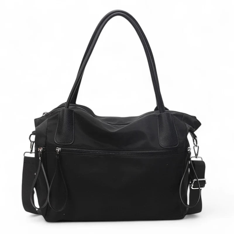 Sac à main NARA NOIR en toile résistante, léger et pratique, avec bandoulière ajustable, offrant grande liberté de mouvement pour vos essentiels du quotidien.
